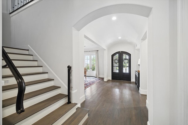 foyer entrance with french doors, arched walkways, dark wood finished floors, stairs, and baseboards
