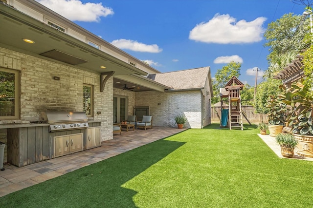 view of yard featuring area for grilling, ceiling fan, a playground, and a patio