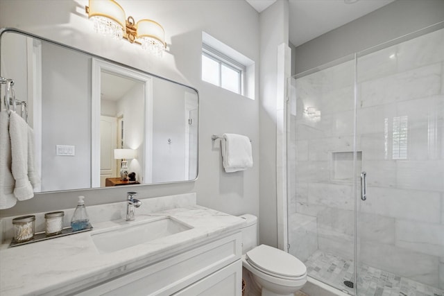 bathroom with a shower stall, toilet, and vanity