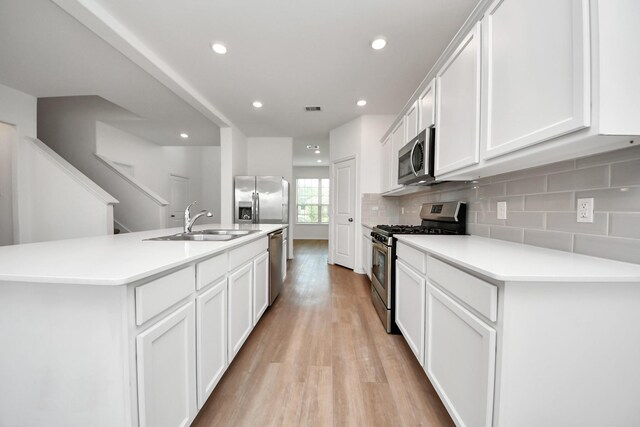 24063 Hawthorn Lakes Dr, New Caney, TX 77357 - kitchen with stainless steel appliances, light wood-style flooring, a sink, tasteful backsplash, and recessed lighting