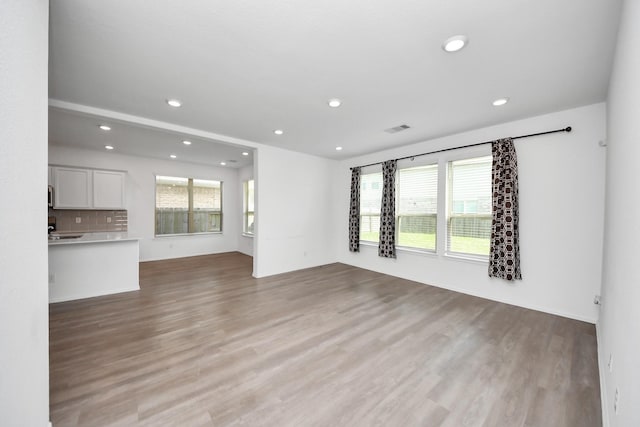 24063 Hawthorn Lakes Dr, New Caney, TX 77357 - unfurnished living room with light wood-style floors, plenty of natural light, and recessed lighting