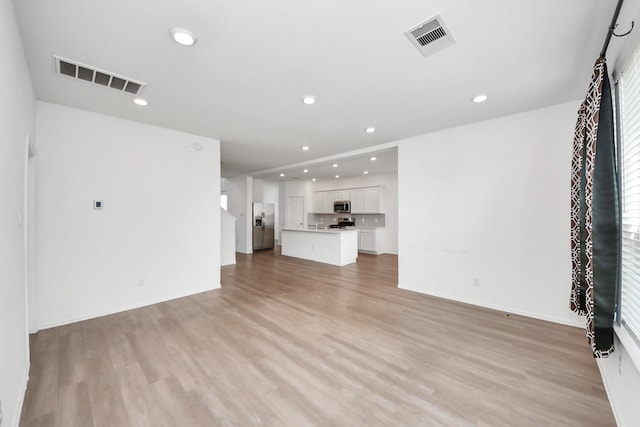 24063 Hawthorn Lakes Dr, New Caney, TX 77357 - unfurnished living room with light wood-type flooring, recessed lighting, and baseboards