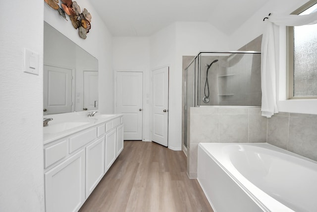24063 Hawthorn Lakes Dr, New Caney, TX 77357 - full bathroom featuring a bath, a stall shower, wood finished floors, double vanity, and vaulted ceiling