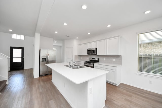 24063 Hawthorn Lakes Dr, New Caney, TX 77357 - kitchen with stainless steel appliances, a sink, a kitchen island with sink, white cabinetry, and tasteful backsplash