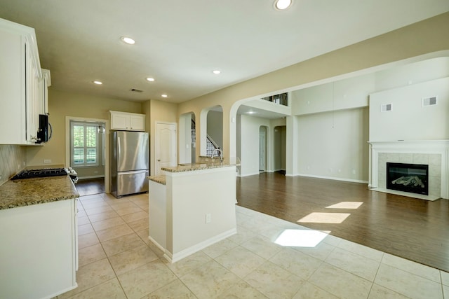 24635 Blue Opal Ln, Katy, TX 77494 - kitchen featuring appliances with stainless steel finishes, arched walkways, light tile patterned floors, light stone counters, and recessed lighting