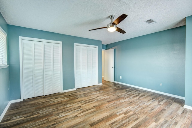 55 Willow Ct, Lake Jackson, TX 77566 - unfurnished bedroom featuring wood finished floors, two closets, baseboards, a textured ceiling, and a ceiling fan