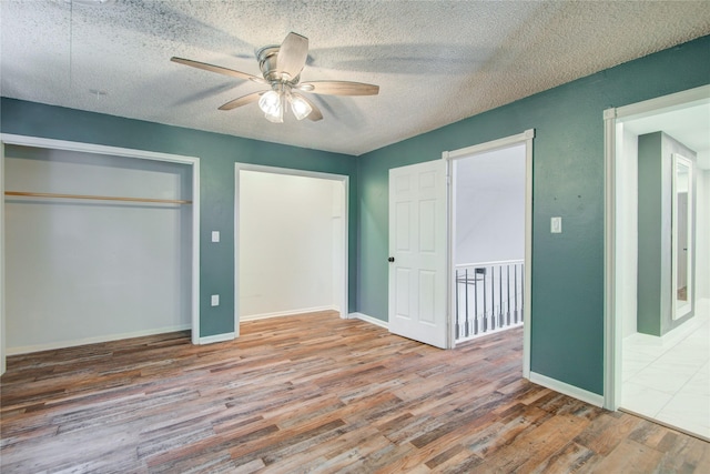 55 Willow Ct, Lake Jackson, TX 77566 - unfurnished bedroom with wood finished floors, a textured ceiling, a closet, baseboards, and a ceiling fan