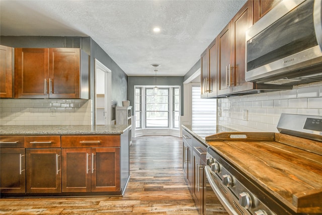 55 Willow Ct, Lake Jackson, TX 77566 - kitchen featuring stainless steel appliances, wood finished floors, a textured ceiling, backsplash, and light stone counters