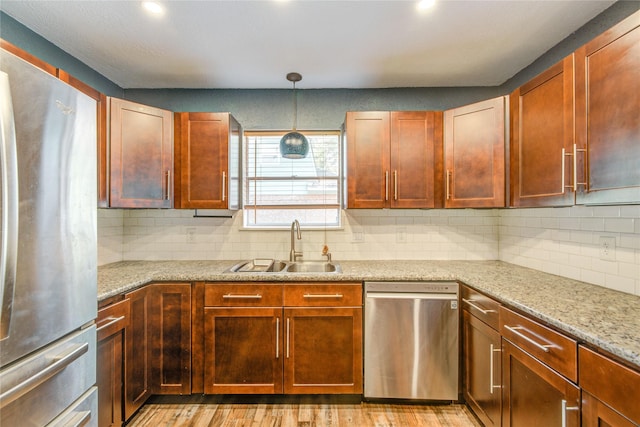 55 Willow Ct, Lake Jackson, TX 77566 - kitchen with stainless steel appliances, a sink, light wood-style flooring, decorative backsplash, and hanging light fixtures