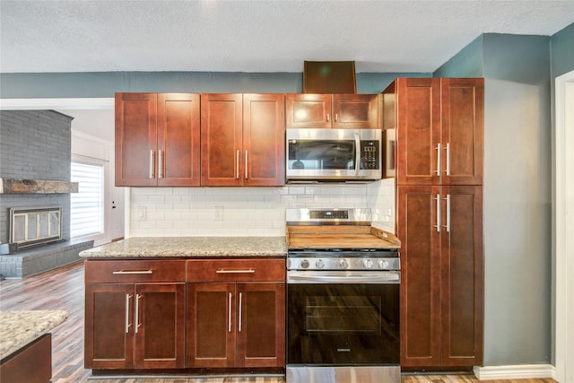 55 Willow Ct, Lake Jackson, TX 77566 - kitchen with appliances with stainless steel finishes, wood finished floors, decorative backsplash, a textured ceiling, and reddish brown cabinets