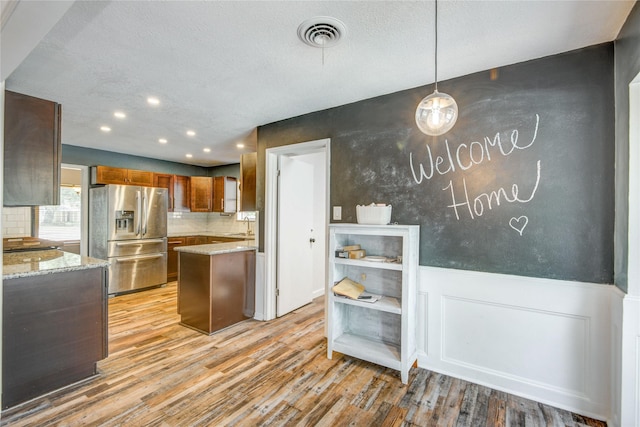 55 Willow Ct, Lake Jackson, TX 77566 - kitchen with stainless steel fridge, light wood-style flooring, light stone counters, recessed lighting, and brown cabinets
