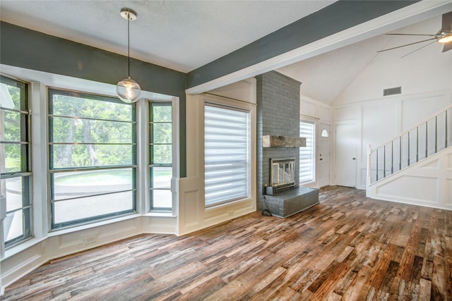 55 Willow Ct, Lake Jackson, TX 77566 - unfurnished living room with a decorative wall, wood finished floors, stairway, vaulted ceiling, and a brick fireplace