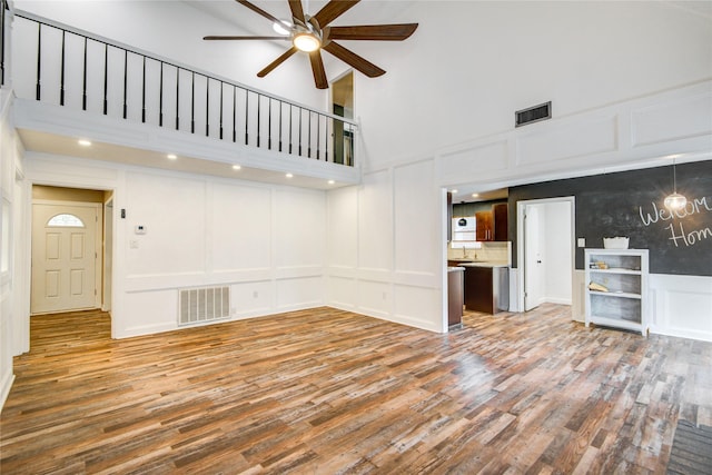 55 Willow Ct, Lake Jackson, TX 77566 - unfurnished living room with a decorative wall, a ceiling fan, a high ceiling, and wood finished floors