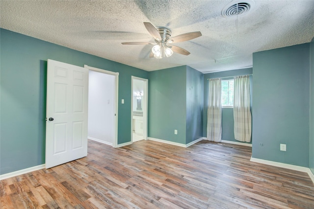 55 Willow Ct, Lake Jackson, TX 77566 - unfurnished bedroom featuring wood finished floors, baseboards, a textured ceiling, connected bathroom, and a ceiling fan