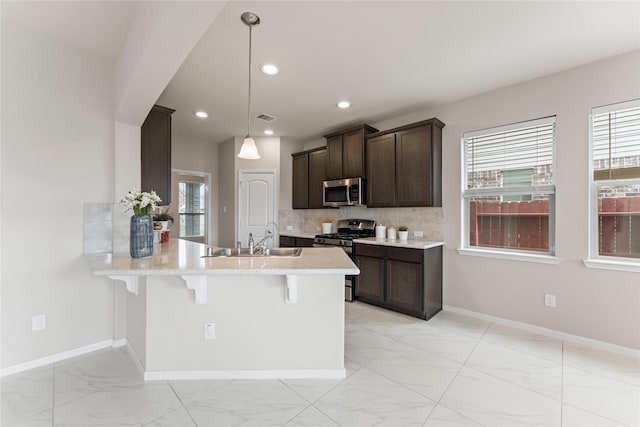 14818 Autumn Long Trl, Humble, TX 77396 - kitchen featuring stainless steel appliances, a sink, light marble finish flooring, a breakfast bar, and a peninsula
