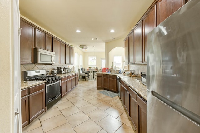 1610 Mason Knights Dr, Katy, TX 77493 - kitchen featuring stainless steel appliances, decorative backsplash, recessed lighting, arched walkways, and light tile patterned floors