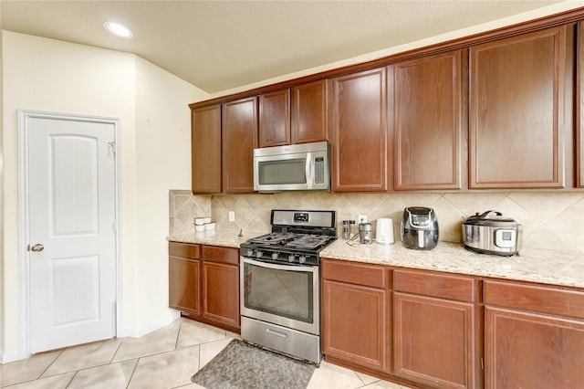 1610 Mason Knights Dr, Katy, TX 77493 - kitchen with appliances with stainless steel finishes, tasteful backsplash, light stone counters, light tile patterned flooring, and recessed lighting