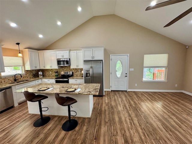 534 Oakdale Dr, Huntsville, TX 77320 - kitchen with stainless steel appliances, a sink, white cabinets, dark wood-type flooring, and high vaulted ceiling