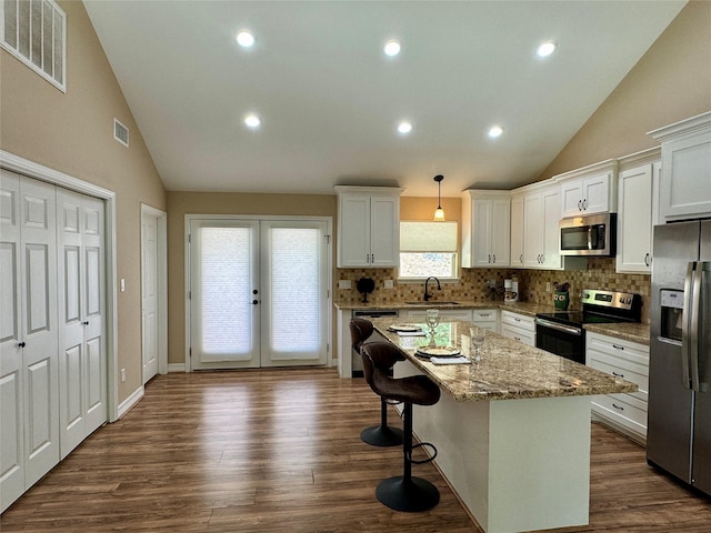 534 Oakdale Dr, Huntsville, TX 77320 - kitchen featuring stainless steel appliances, a sink, tasteful backsplash, white cabinets, and a kitchen island