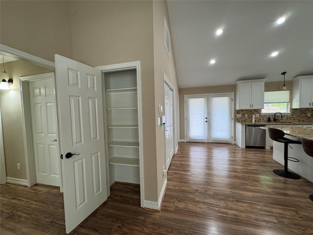 534 Oakdale Dr, Huntsville, TX 77320 - kitchen featuring stainless steel dishwasher, white cabinets, decorative backsplash, baseboards, and high vaulted ceiling