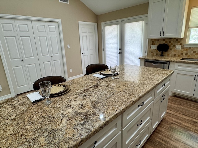 534 Oakdale Dr, Huntsville, TX 77320 - kitchen with white cabinetry, lofted ceiling, light stone countertops, backsplash, and wood finished floors