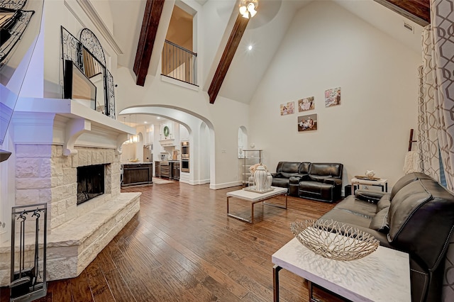 105 Checkerbloom Ct, Montgomery, TX 77316 - living room featuring arched walkways, high vaulted ceiling, baseboards, wood finished floors, and a stone fireplace