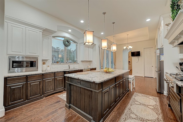 105 Checkerbloom Ct, Montgomery, TX 77316 - kitchen with white cabinets, appliances with stainless steel finishes, dark brown cabinetry, a kitchen island, and tasteful backsplash