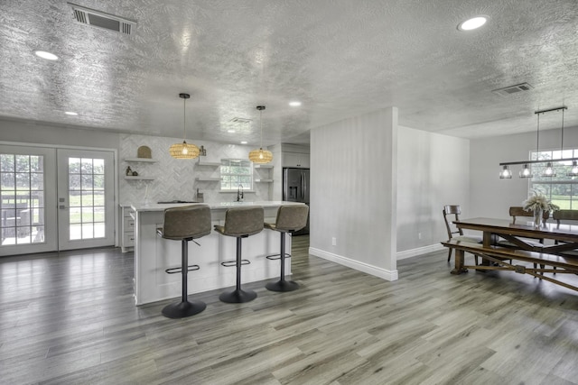 3508 Dick Barnes Loop, Bedias, TX 77831 - kitchen with open shelves, light countertops, a textured ceiling, wood finished floors, and plenty of natural light
