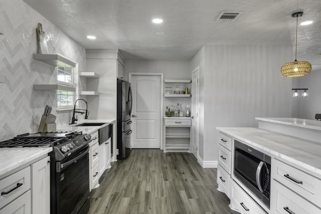 3508 Dick Barnes Loop, Bedias, TX 77831 - kitchen featuring open shelves, black gas range oven, stainless steel microwave, freestanding refrigerator, and dark wood-style floors