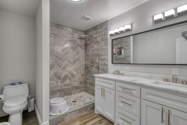 3508 Dick Barnes Loop, Bedias, TX 77831 - full bathroom with wood finished floors, toilet, a tile shower, and a textured ceiling