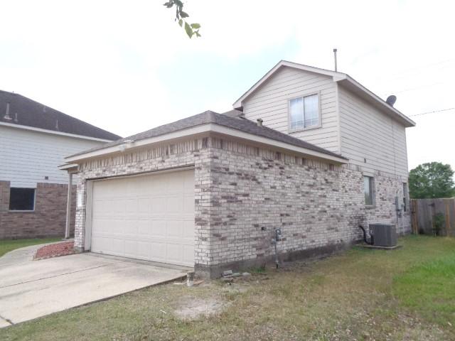 21031 Noelle Ct, Humble, TX 77338 - view of property exterior with a garage, driveway, central AC unit, and a lawn
