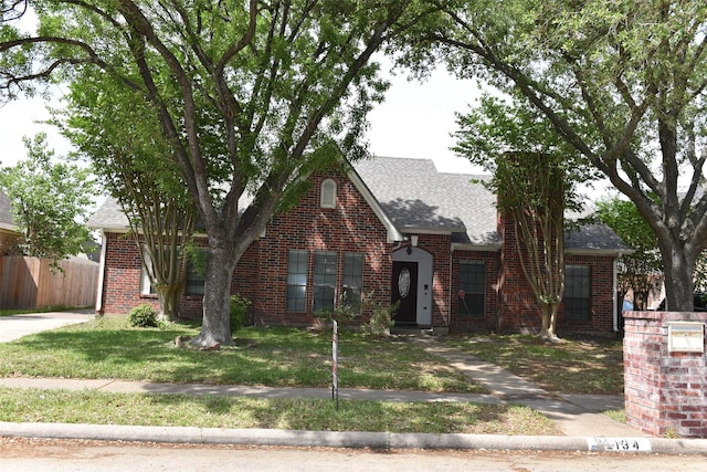 view of front of home featuring brick siding and roof with shingles