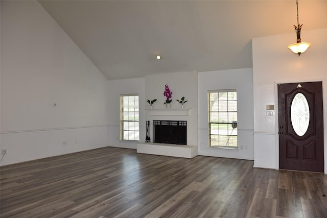 entryway with dark wood-type flooring, healthy amount of natural light, a fireplace, and high vaulted ceiling