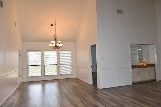 unfurnished dining area featuring high vaulted ceiling, a chandelier, dark wood finished floors, and baseboards