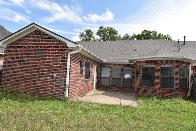 back of property with brick siding, a patio area, a yard, and a shingled roof