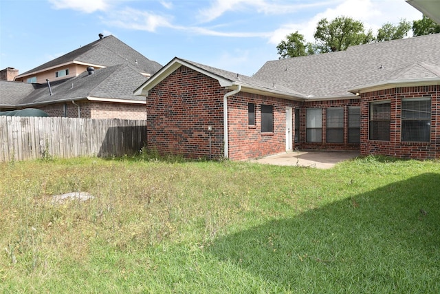 rear view of property featuring brick siding, a patio, and roof with shingles