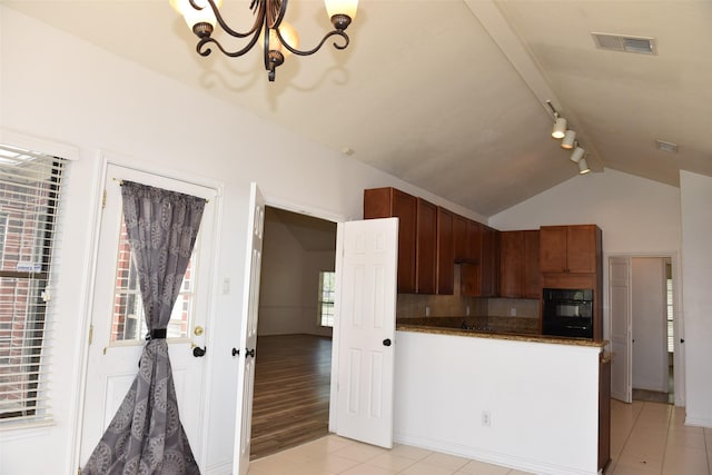 kitchen with oven, rail lighting, a chandelier, light tile patterned floors, and lofted ceiling