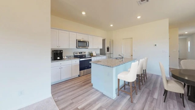18765 Lucas Michael Way, New Caney, TX 77357 - kitchen with stainless steel appliances, white cabinetry, a kitchen island with sink, a sink, and recessed lighting
