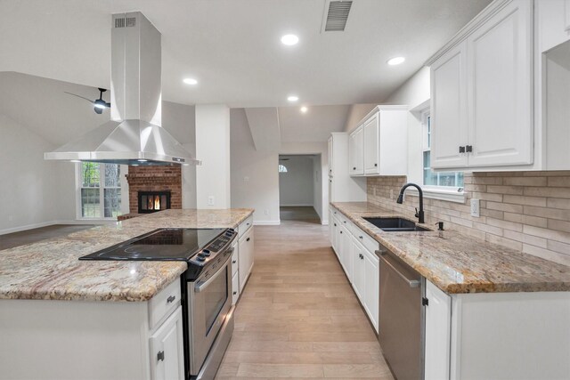 125 Park Way, Conroe, TX 77356 - kitchen with stainless steel appliances, a sink, island exhaust hood, baseboards, and white cabinetry