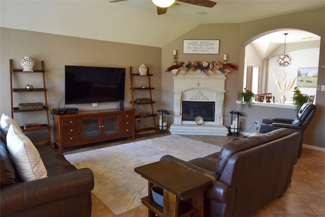 2603 Briar Rose Ct, Pearland, TX 77584 - tiled living room with a ceiling fan, lofted ceiling, arched walkways, a glass covered fireplace, and baseboards