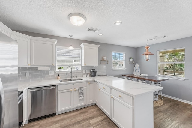 424 Angel Wing St, Surfside Beach, TX 77541 - kitchen with stainless steel appliances, a sink, a peninsula, a textured ceiling, and white cabinets