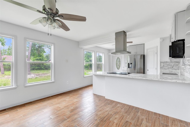 18586 Summer Hills Blvd, Porter, TX 77365 - kitchen featuring black appliances, a peninsula, island range hood, light stone countertops, and a sink