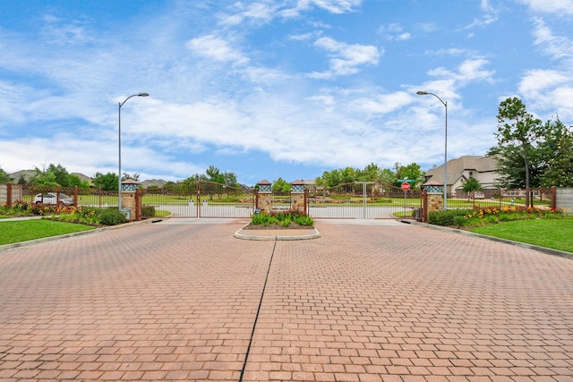 18910 Winding Atwood Ln, Tomball, TX 77377 - view of decorative street featuring a gate, curbs, traffic signs, and a gated entry