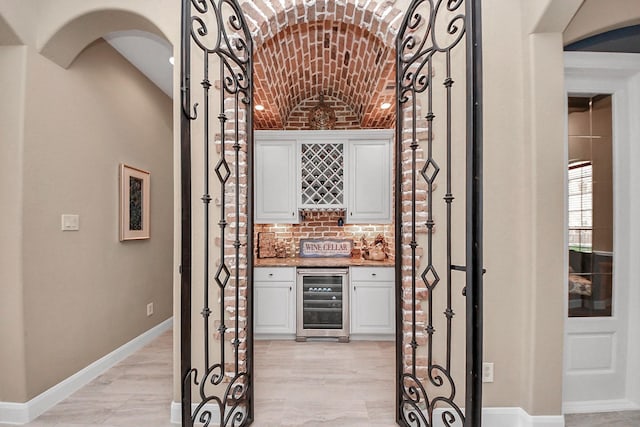 18910 Winding Atwood Ln, Tomball, TX 77377 - wine room featuring wine cooler, brick ceiling, a dry bar, baseboards, and arched walkways