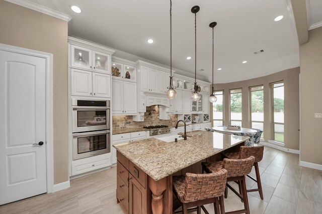 18910 Winding Atwood Ln, Tomball, TX 77377 - kitchen with appliances with stainless steel finishes, a sink, baseboards, backsplash, and a large island with sink