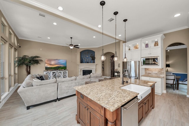 18910 Winding Atwood Ln, Tomball, TX 77377 - kitchen with arched walkways, appliances with stainless steel finishes, a sink, a fireplace, and ceiling fan