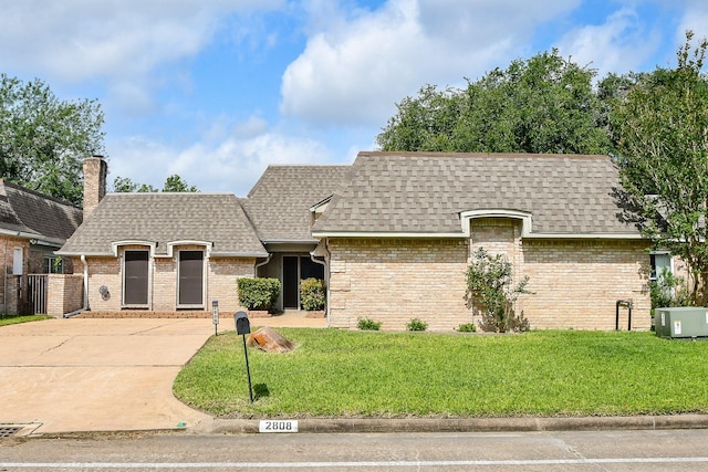 2808 Cypress Point Dr, Missouri City, TX 77459 - french country home featuring roof with shingles, a front lawn, brick siding, a chimney, and concrete driveway