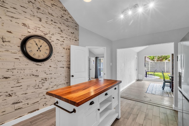 9802 Pale Star Dr, Houston, TX 77064 - kitchen featuring wooden counters, an accent wall, lofted ceiling, white cabinetry, and light wood-type flooring