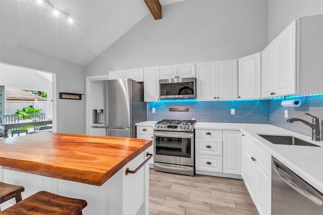 9802 Pale Star Dr, Houston, TX 77064 - kitchen with appliances with stainless steel finishes, a sink, high vaulted ceiling, backsplash, and white cabinets