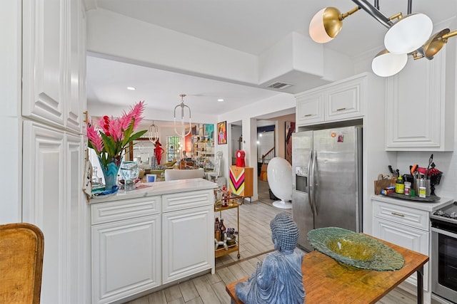 2719 Alabama St, Houston, TX 77004 - kitchen with stainless steel appliances, white cabinetry, light countertops, light wood-style flooring, and decorative light fixtures